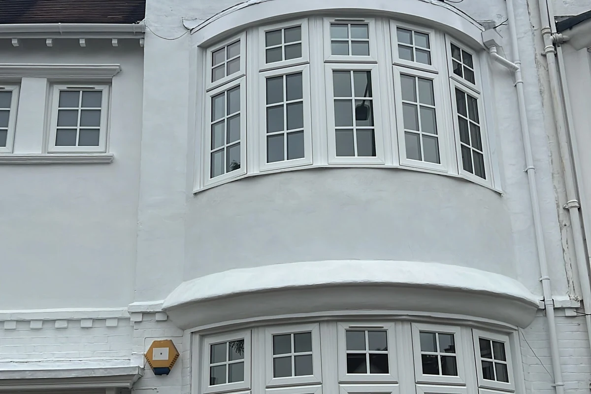 Repainted white-rendered period terrace front with bay windows in Hampstead